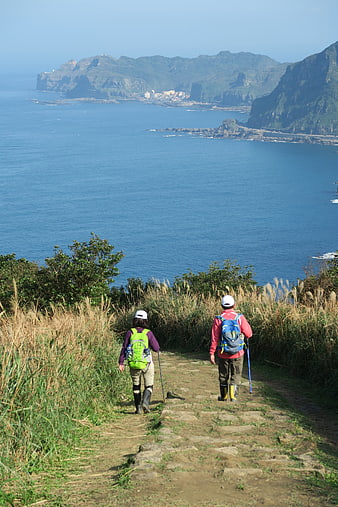Hikers on Coastal Trail Overlooking Ocean and Mountains