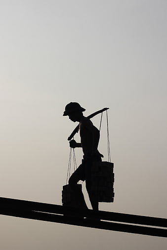 Silhouette of construction worker carrying heavy load