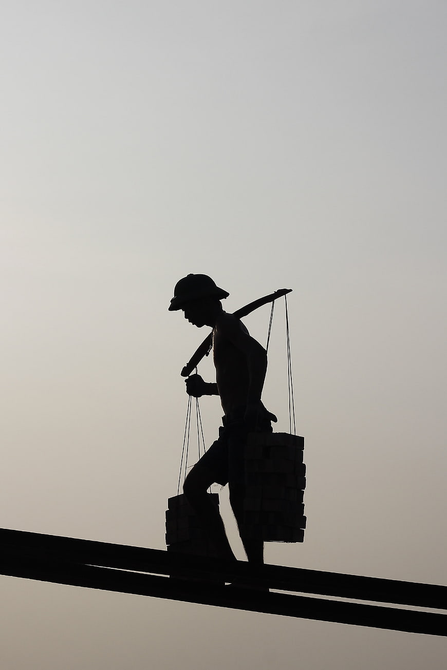 Silhouette of construction worker carrying heavy load