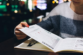 Woman reading restaurant menu at night