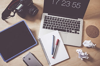 Flat lay workspace with laptop, camera, tablet, and notebook