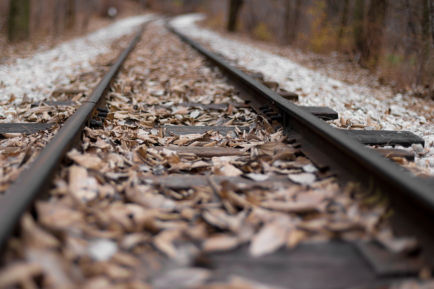 Low angle view of railway tracks covered in autumn leaves and snow
