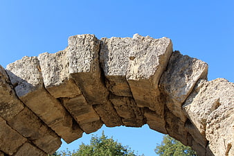 Ancient Greek Stone Arch Ruins Against Blue Sky