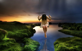 Surreal woman on swing over mossy rocks at sunset