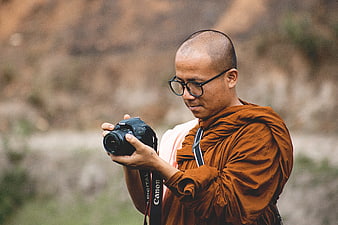 Buddhist Monk Photographing with DSLR Camera Outdoors