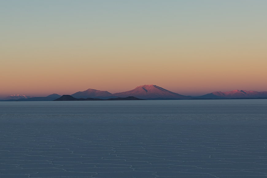 Frozen Lake Landscape with Distant Mountains at Sunset