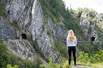 Blonde woman hiking in mountain landscape with tunnels