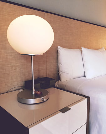 Modern spherical lamp on bedside table in hotel room