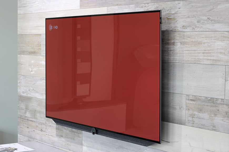 Modern flat-screen TV with red display mounted on wood wall
