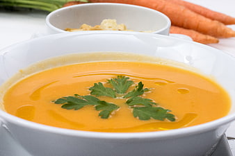 Creamy Carrot Soup Garnished With Fresh Parsley In White Bowl
