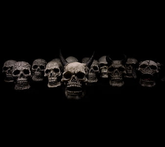 Row of spooky skulls and demons on black background