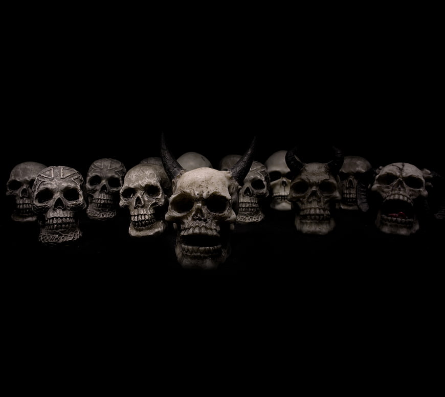 Row of spooky skulls and demons on black background