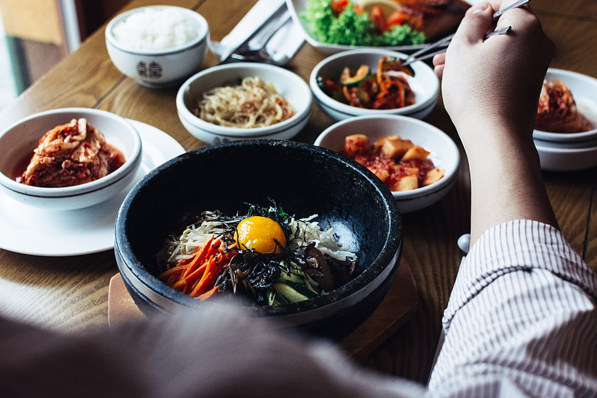 Korean Bibimbap with Kimchi Side Dishes on Wooden Table