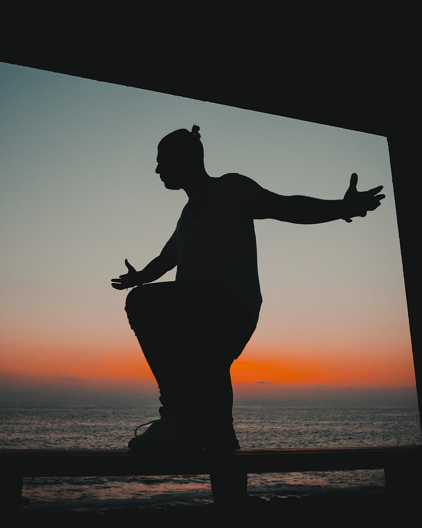 Silhouette of man meditating on beach at sunset