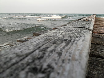 Weathered wooden pier railing overlooking choppy ocean waves