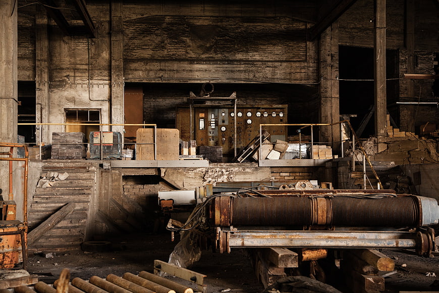 Abandoned industrial factory interior with rusty machinery and control panel