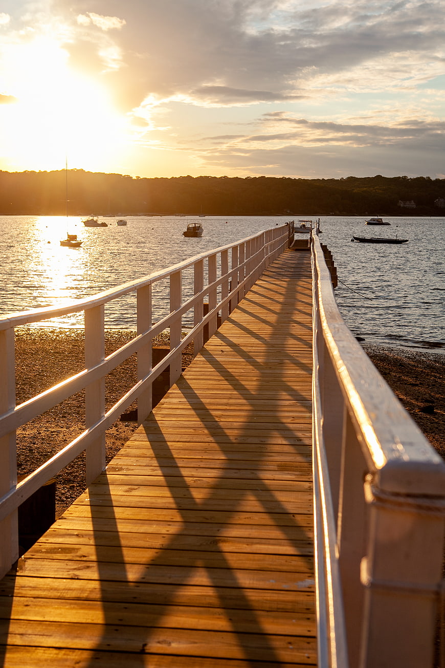 Sunset over wooden pier with boats on calm water