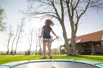 Young girl jumping on trampoline in sunny backyard