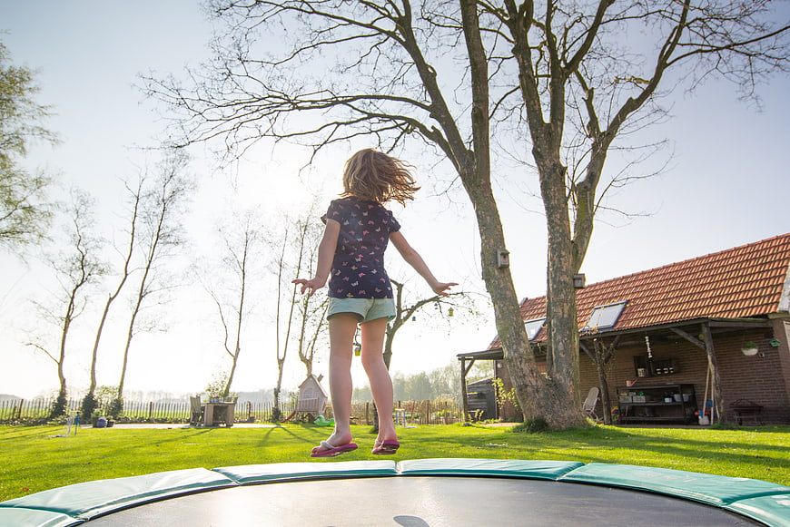 Young girl jumping on trampoline in sunny backyard