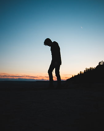 Silhouette of a man standing alone at sunset