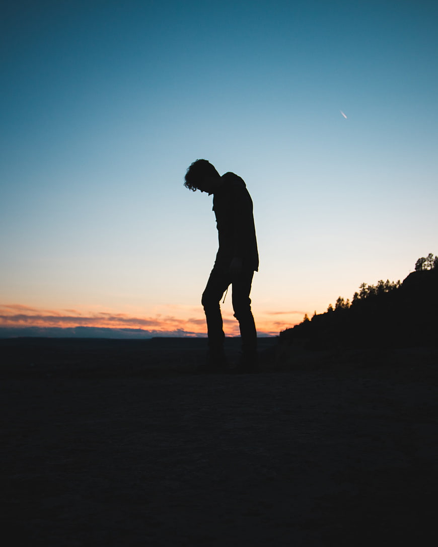 Silhouette of a man standing alone at sunset