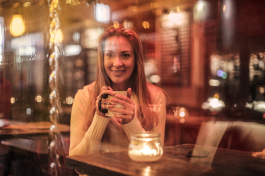 Smiling Woman Holding Coffee Mug in Cozy Cafe