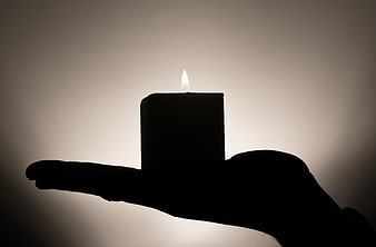 Silhouette of Hand Holding Lit Candle Against Gradient Background