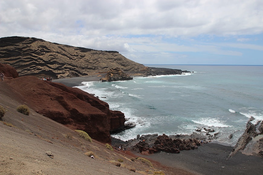 Volcanic red cliffs and black sand beach in Lanzarote