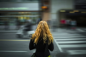 Woman with blonde hair standing on busy city street