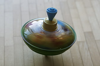 Spinning colorful plastic toy top on wooden floor