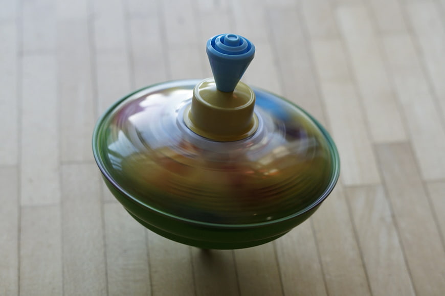Spinning colorful plastic toy top on wooden floor