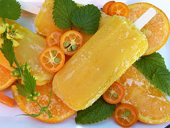 Frozen orange popsicles with kumquats and mint leaves