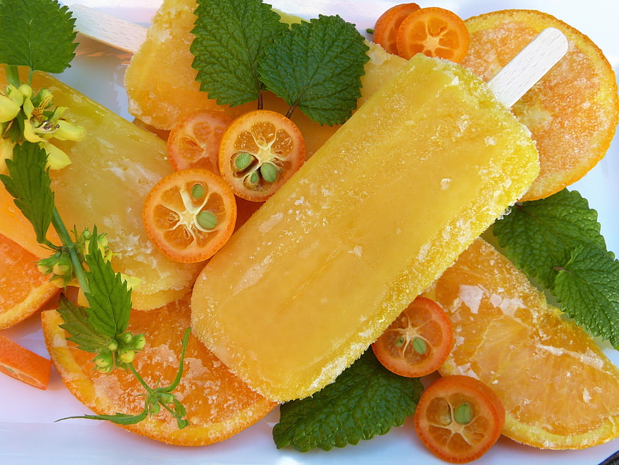 Frozen orange popsicles with kumquats and mint leaves