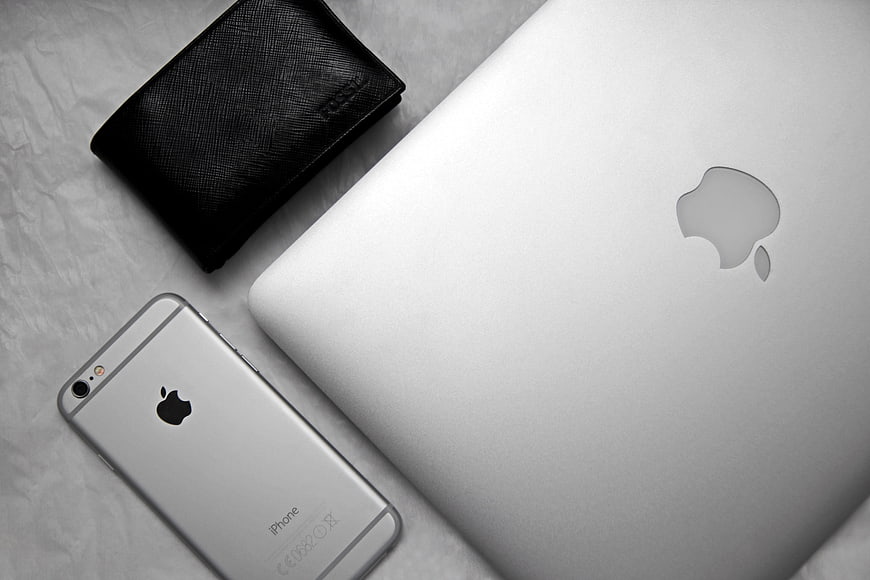 Silver Apple iPhone and MacBook with Black Wallet on White Background