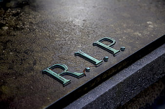 Close-up of weathered RIP letters on a stone grave marker