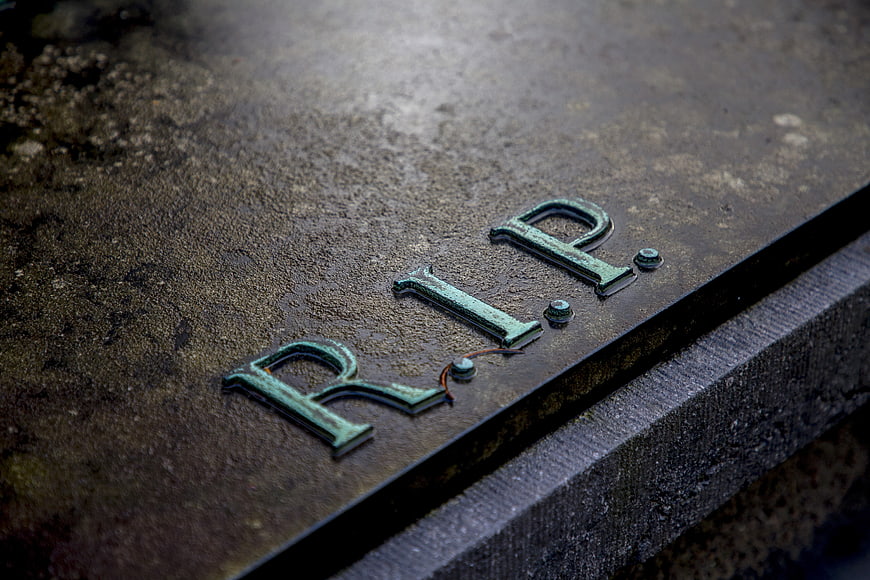 Close-up of weathered RIP letters on a stone grave marker