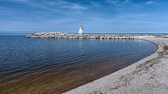 White Lighthouse on Rocky Breakwater with Blue Sky