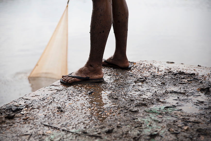 Muddy legs standing on wet concrete near water