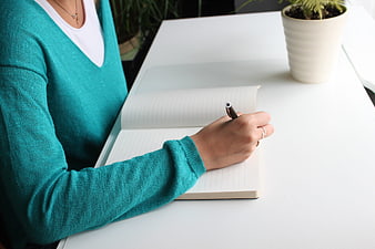 Woman Writing in Notebook on White Desk