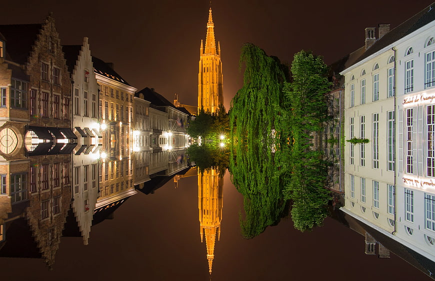 Upside-down night view of Bruges canal and church tower