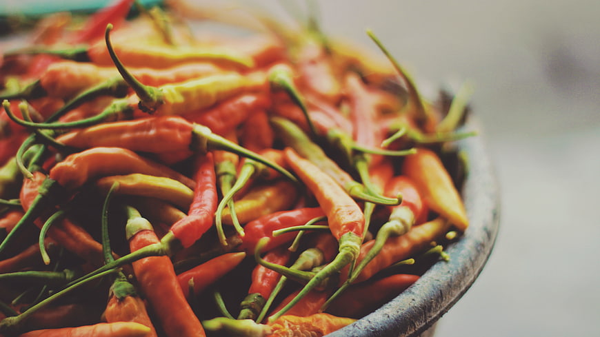 Close-up of fresh red and green chili peppers in a bowl