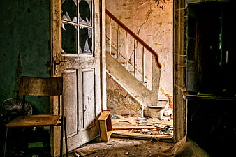 Dilapidated Interior of Abandoned House with Broken Door and Stairs