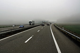 Foggy Highway with Cars and Trucks Driving on Asphalt Road