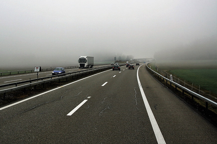 Foggy Highway with Cars and Trucks Driving on Asphalt Road