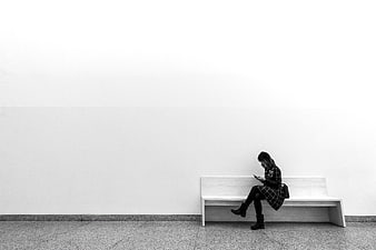 Minimalist Black and White Woman Sitting on Bench Using Phone