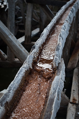 Salt water flowing through a rustic wooden sluice channel