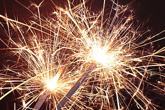 Close-up of burning sparklers with bright golden sparks on black background