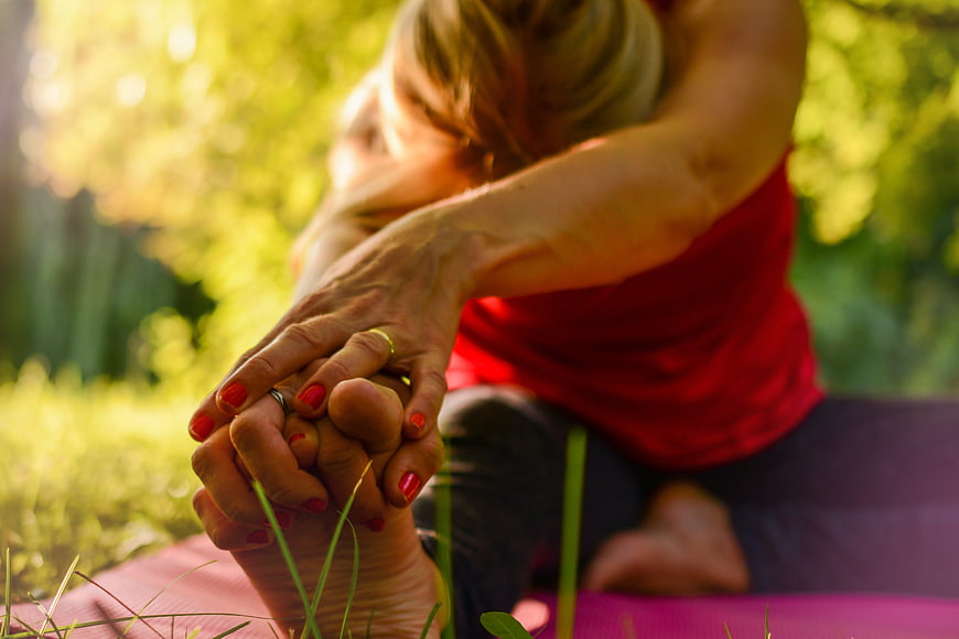 Woman stretching foot in yoga pose outdoors at golden hour