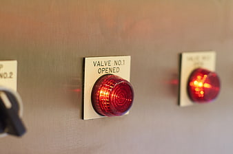 Close-up of glowing red industrial valve indicator light