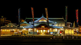 Traditional Japanese Onsen Building At Night With Illuminated Roofs